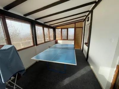 a ping pong table in a room with windows at DeTY’s Guest House in Drachevo