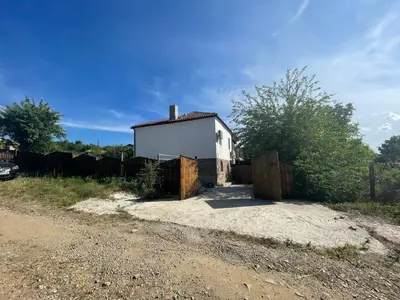 a small white house with a fence and a dirt road at DeTY’s Guest House in Drachevo