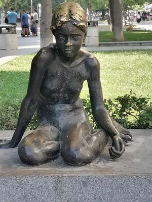 a statue of a young boy sitting on the ground at Оазис 1 във Варна in Varna City