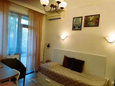 a bedroom with a bed and a table and a window at Оазис 2 във Варна in Varna City