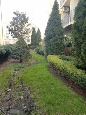 a garden with trees and grass in front of a building at Жасмин клуб in Sunny Beach