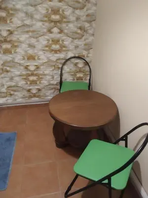 a wooden table and two green chairs in a room at Апартамент стоенчо хаджииванов,10 in Varna City