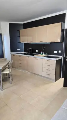 a kitchen with white cabinets and a table and a dining room at Apart-Hotel Argo in Lozenets