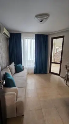 a living room with a couch and blue curtains at Apart-Hotel Argo in Lozenets