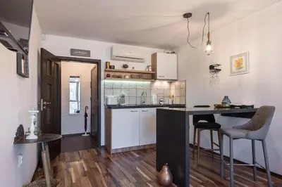 a kitchen with white cabinets and a black counter top at Студио в близост до Община Варна in Varna City