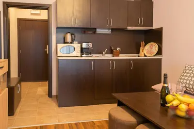 a kitchen with brown cabinets and a table with fruit on it at Апартамент Царски бриз in Sozopol