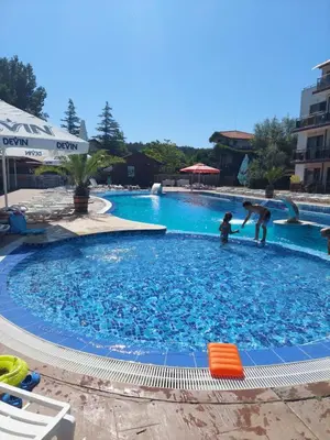 two people playing in a large blue swimming pool at Апартамент Царски бриз in Sozopol