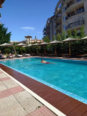 a person swimming in a swimming pool with umbrellas at Sunny beach apartaments in Sunny Beach