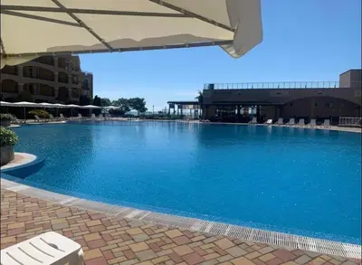 a large blue swimming pool with a white umbrella at Midia Family Resort, Aheloy in Aheloy