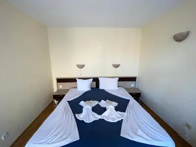 a bedroom with a bed with white sheets and wine glasses at VECHNA R 18 Studio Sunny Beach in Sunny Beach