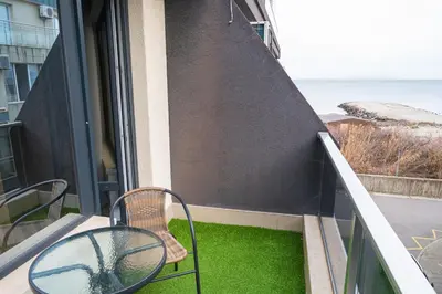 a balcony with two chairs and a table and a window at Sea View Apartment with Free Parking in Pomorie