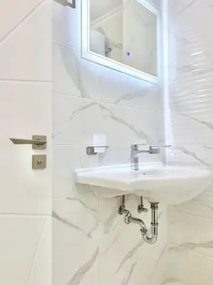 a white bathroom with a sink and a mirror at Sea View Apartment with Free Parking in Pomorie