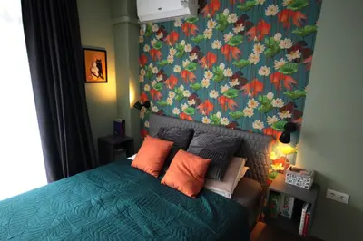 a bedroom with a blue bed with a floral wallpaper at Apartment Daisy Grand Kamelia in Sunny Beach