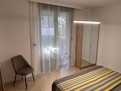 a bedroom with a bed and a chair and a window at Eve Santa Marina Apartments II - sea, pools, relax in Sozopol