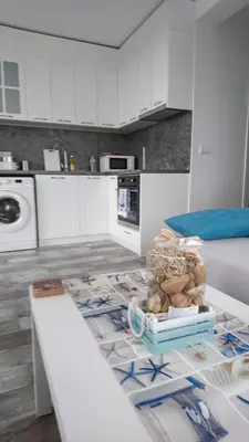 a kitchen with white cabinets and a table in a room at Сити бийч вю in Tsarevo