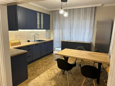a kitchen with blue cabinets and a wooden table at Niya Apartment Bourgas in Burgas City