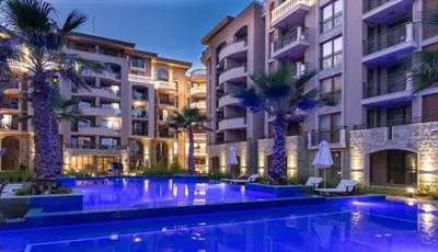 a swimming pool with palm trees in front of a building at Deluxe Appartement in Cascadas Resort Sunny Beach in Sunny Beach