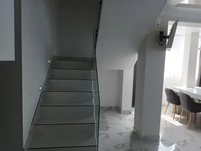 a glass staircase in a room with a table at Apartament Milenium in Pomorie