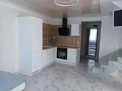 a kitchen with white cabinets and marble flooring at Apartament Milenium in Pomorie