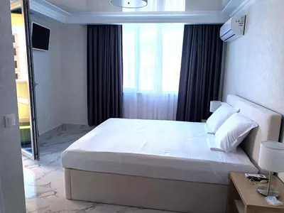 a bedroom with a large white bed with a window at Apartament Milenium in Pomorie