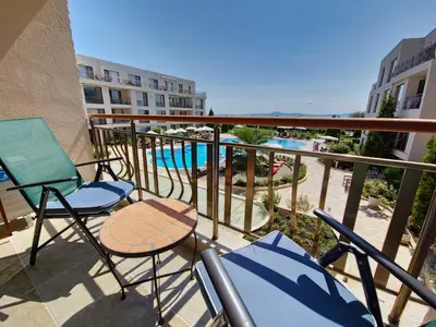 a balcony with chairs and a table and a swimming pool at Diamond Beach Sarafovo by KP in Burgas City