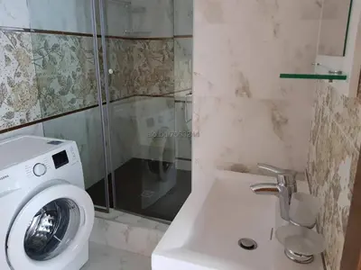a bathroom with a washing machine next to a sink at Апартамент в Комплекс Милениум in Pomorie