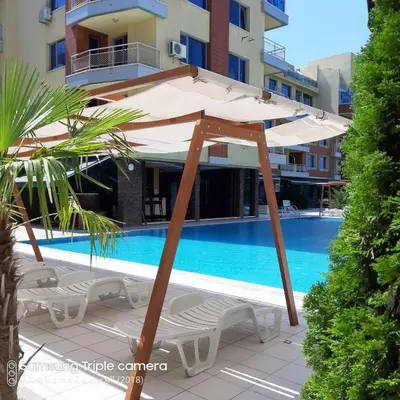 a umbrella and chairs next to a swimming pool at Апартамент в Комплекс Милениум in Pomorie