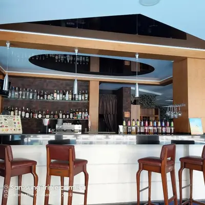 a bar with chairs and a counter with liquor bottles at Апартамент в Комплекс Милениум in Pomorie
