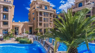 a resort with a pool and palm trees in front of a building at Апартамент под наем С208 в Афродита Гарденс in Sunny Beach