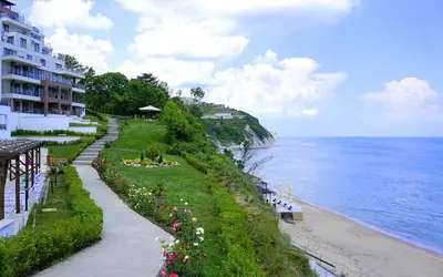 a walkway next to a beach with a building at Byala Cliff Sea View Suite in Byala