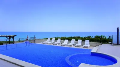 a swimming pool with chairs and the ocean in the background at Byala Cliff Sea View Suite in Byala