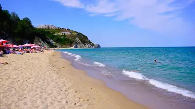 a beach with umbrellas and people swimming in the ocean at Byala Cliff Sea View Suite in Byala