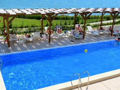 a group of people sitting around a swimming pool at Byala Cliff Sea View Penthouse in Byala