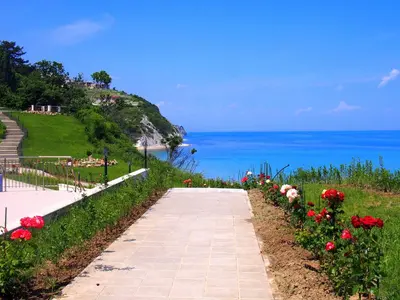 a walkway with flowers on a hill next to the ocean at Byala Cliff Sea View Penthouse in Byala