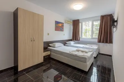 a bedroom with two beds and a cabinet and a window at Стаи за гости ПИРОТСКА 39 in Burgas City