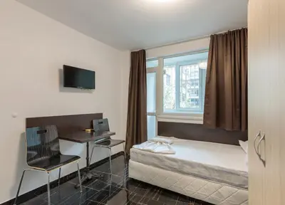 a bedroom with a bed and a desk and a window at Стаи за гости ПИРОТСКА 39 in Burgas City