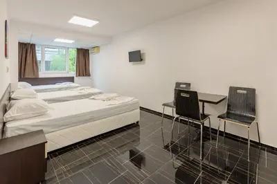 a bedroom with a bed and a desk and chairs at Стаи за гости ПИРОТСКА 39 in Burgas City