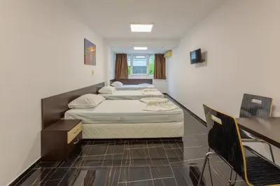 a room with two beds and a desk in it at Стаи за гости ПИРОТСКА 39 in Burgas City
