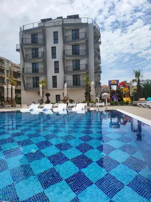 a swimming pool with chairs and a building at хотел ADDRESS in Ravda