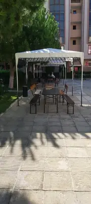a group of tables and benches under a white canopy at Apartmány Rose Residence Nesebar in Sunny Beach