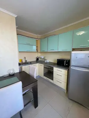a kitchen with a table and a stainless steel refrigerator at Apart hotel Gallery A in Sunny Beach