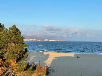 a beach with people sitting on the sand and the ocean at Apart hotel Gallery L in Sunny Beach