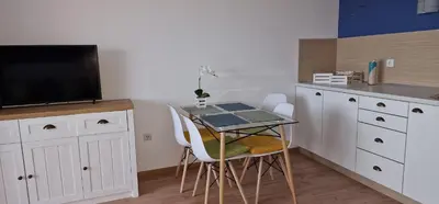 a small kitchen with a table with chairs and a tv at Studio Fresh in Sozopol