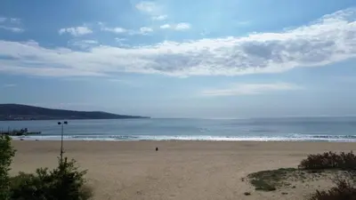 a beach with a person walking on the sand at Apart hotel Gallery Studio in Sunny Beach