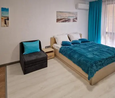 a bedroom with a bed and a chair at Апарткомплекс Амара Слънчев Бряг Студио 13 in Sunny Beach