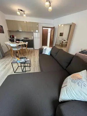 a living room with a black couch and a kitchen at Studio Marrone on Bogoridi in Burgas City