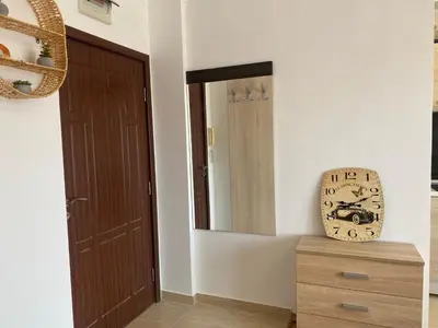 a room with a door and a clock on a dresser at SUMMER BREEZE 110 Cozi Studio in Sunny Beach