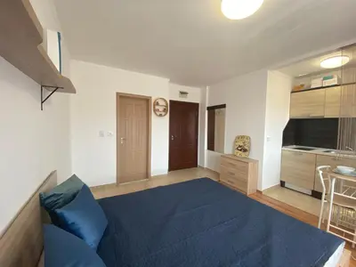 a living room with a blue bed and a kitchen at SUMMER BREEZE 110 Cozi Studio in Sunny Beach