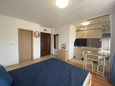 a bedroom with a blue bed and a kitchen at SUMMER BREEZE 110 Cozi Studio in Sunny Beach