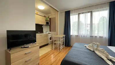 a hotel room with a bed and a flat screen tv at SUMMER BREEZE 110 Cozi Studio in Sunny Beach